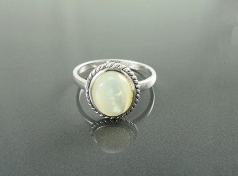 Une bague en argent avec une pierre en nacre blanche sertie dans un motif en forme de corde de style ancien. Un bijou artisanal fait main localement avec des matières naturelles. KRAMIKE est une boutique de qualité recommandée par ses milliers de clients.