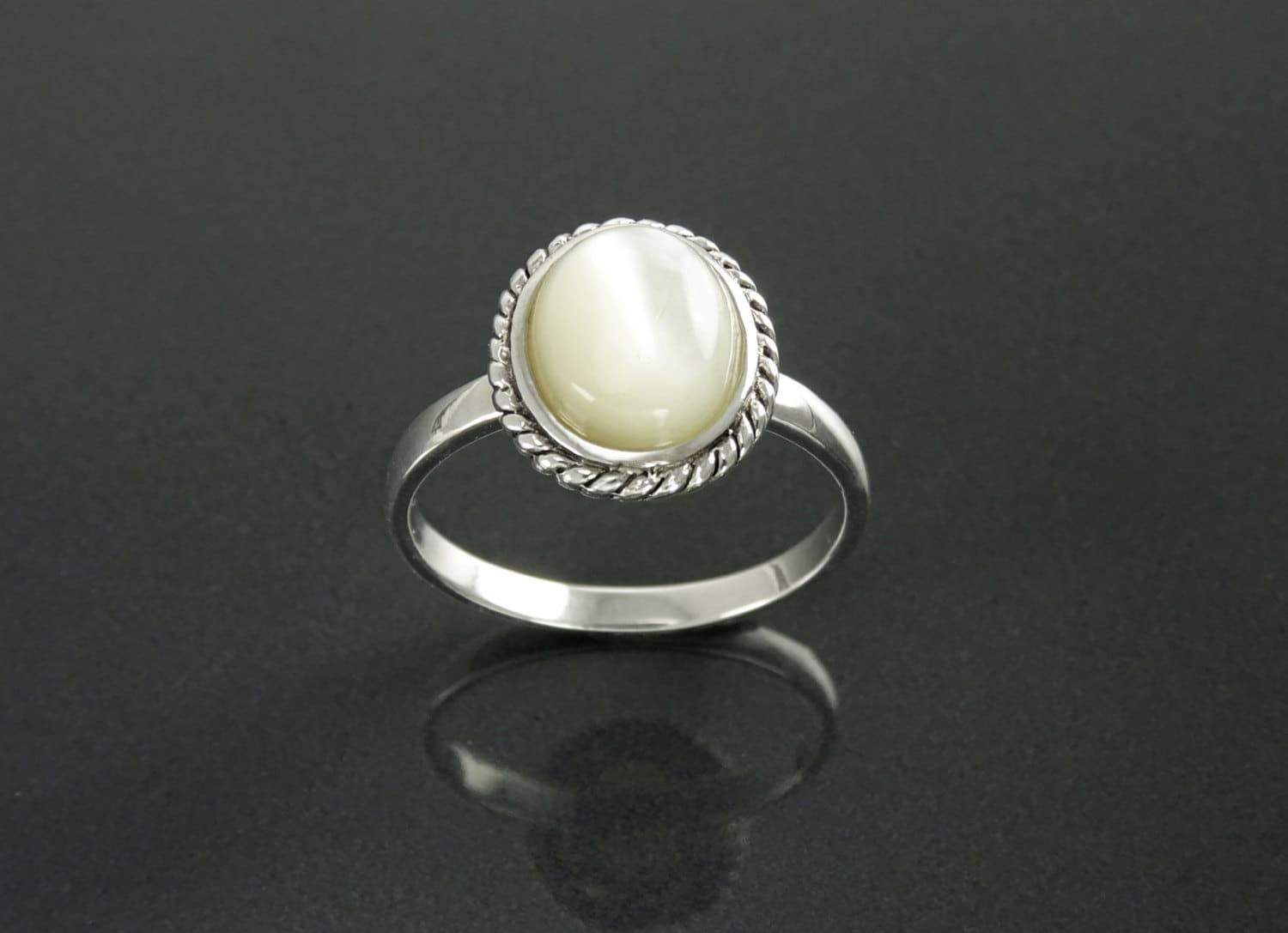 Une bague en argent 925 sertie d'une nacre ovale blanche sertie dans une bordure de style ancien en forme de corde. Un bijou artisanal en matière durable. Fait main localement à Paris par KRAMIKE, une petite boutique de confiance recommandée par ses milliers de clients.