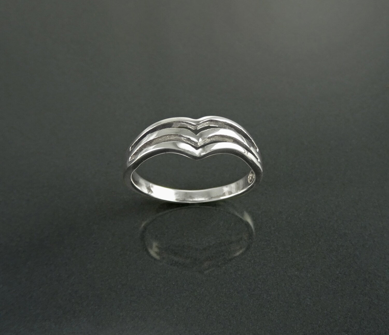 Une bague en argent 925 avec un design unique composé de trois bandes courbes formant un V.