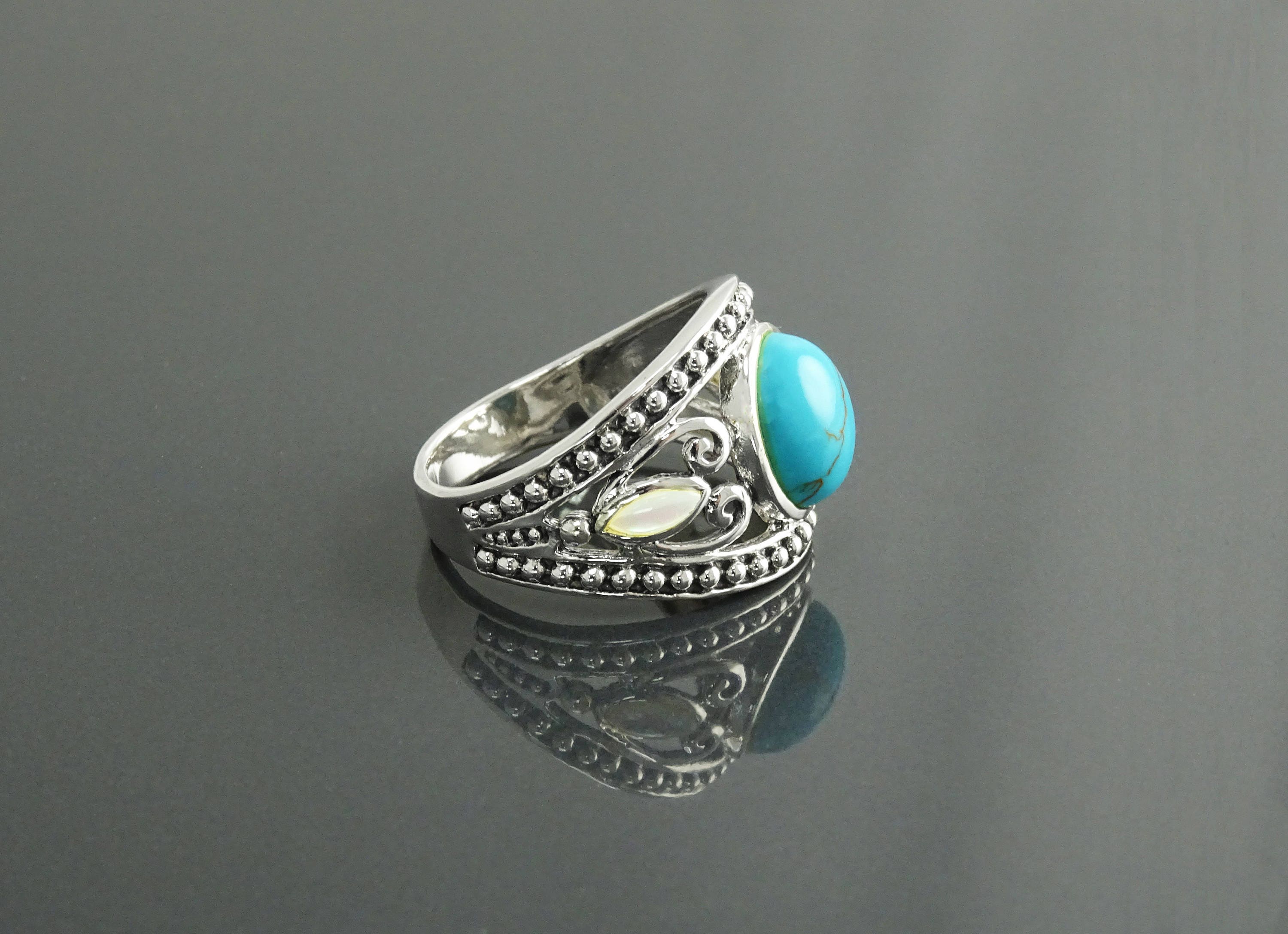 Une bague boho en argent 925 avec une pierre turquoise et une nacre blanche serties dans un motif décoratif vintage.