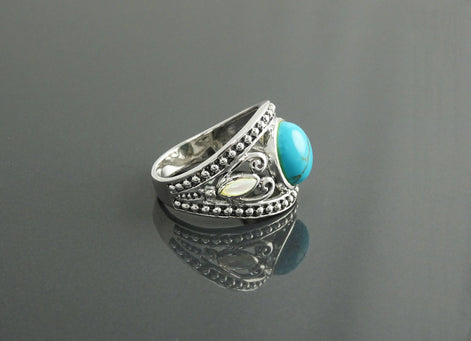 Une bague boho en argent 925 avec une pierre turquoise et une nacre blanche serties dans un motif décoratif vintage.