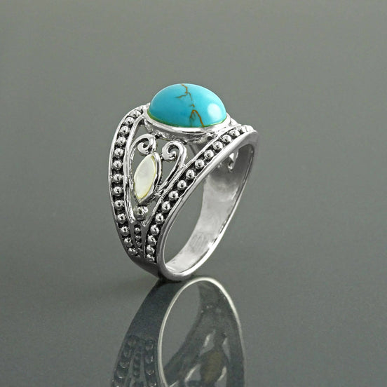Une bague bohème en argent avec une pierre turquoise et une incrustation de nacre blanche. La bague est ornée d'un motif vintage perlé