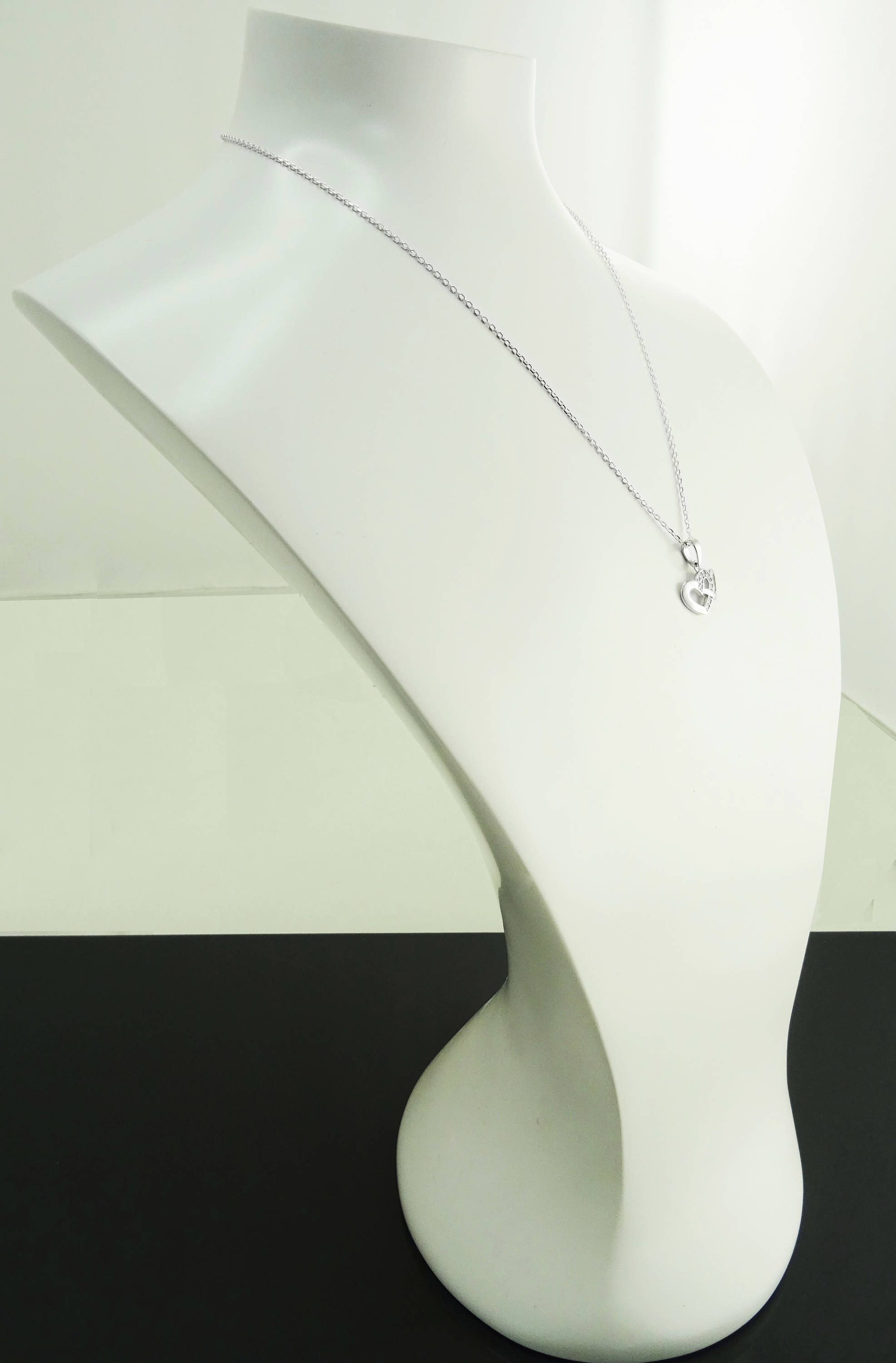 Un collier en chaîne argent avec un petit pendentif en forme de cœur ouvert.