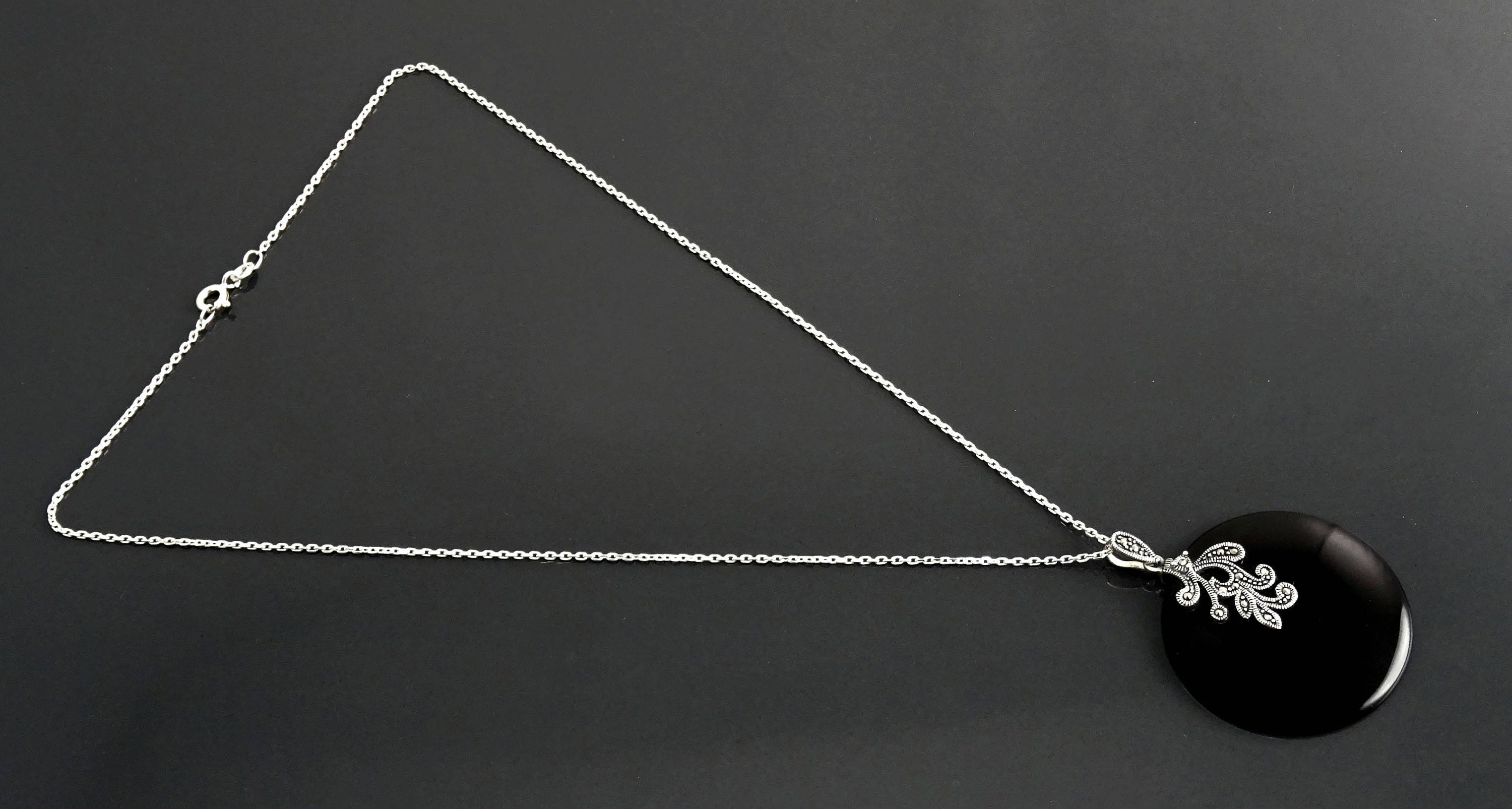 Un collier en chaîne argent massif avec un pendentif en argent 925 et en onyx noir orné d'un motif en filigrane style retro Art Nouveau.