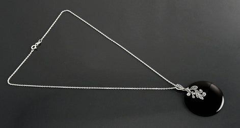 Un collier en chaîne argent massif avec un pendentif en argent 925 et en onyx noir orné d'un motif en filigrane style retro Art Nouveau.