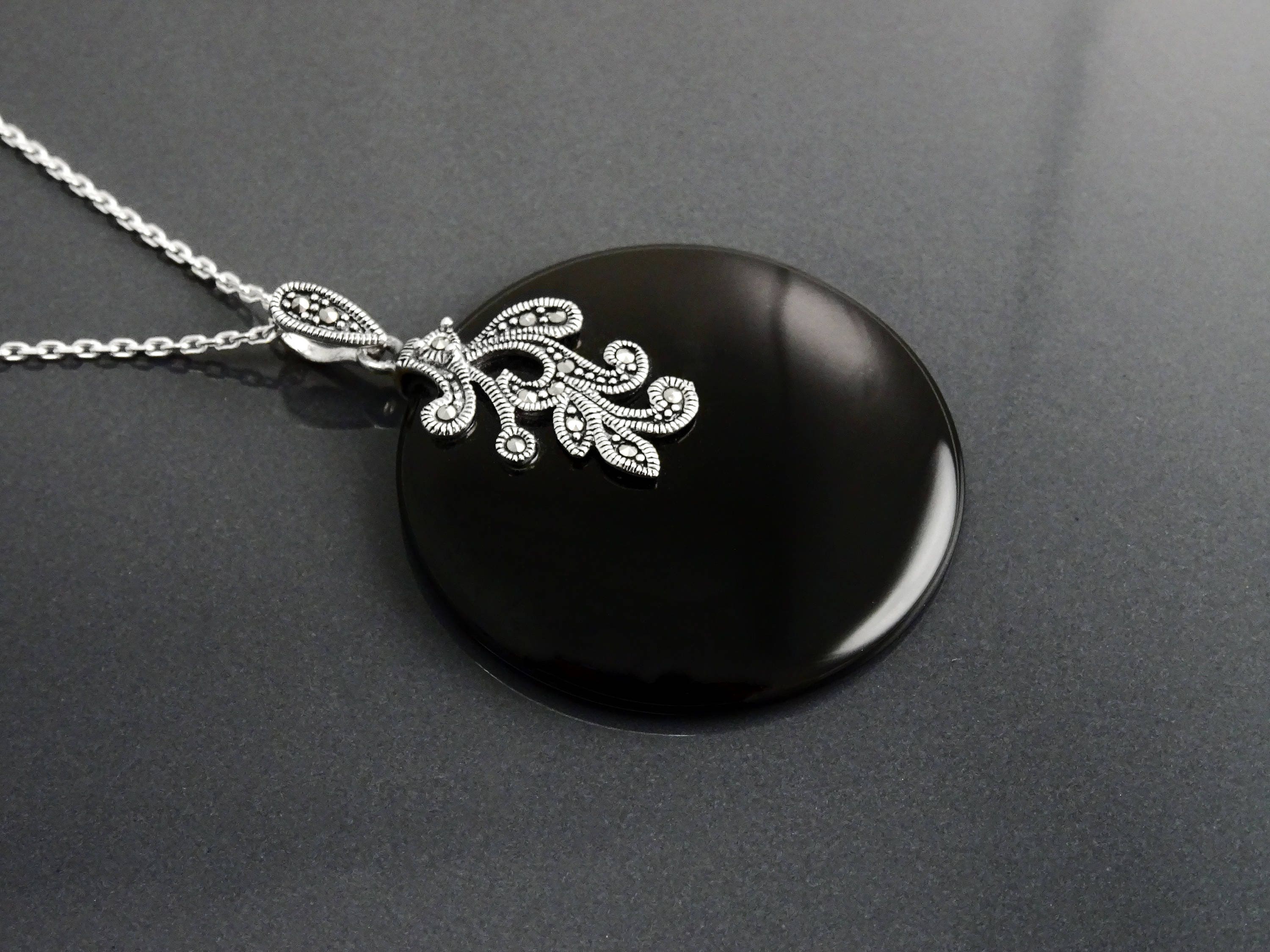 Un collier en argent 925 avec un pendentif en argent 925 et pierre onyx noir orné d'un motif filigrané vintage Art Nouveau.