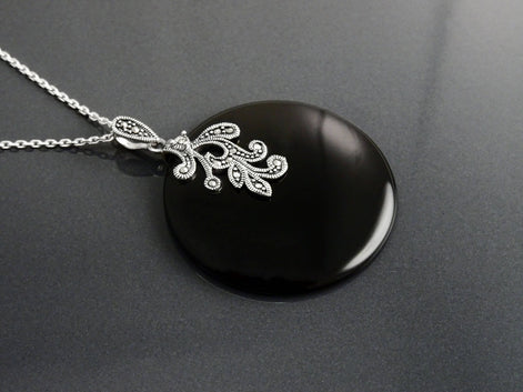 Un collier en argent 925 avec un pendentif en argent 925 et pierre onyx noir orné d'un motif filigrané vintage Art Nouveau.