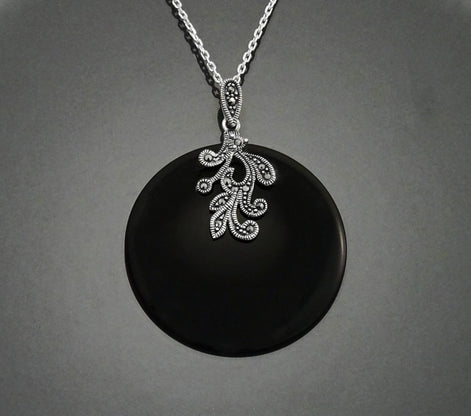 Un collier en argent avec un pendentif en onyx noir orné d'un motif vintage Art Deco détaillé en marcassite.