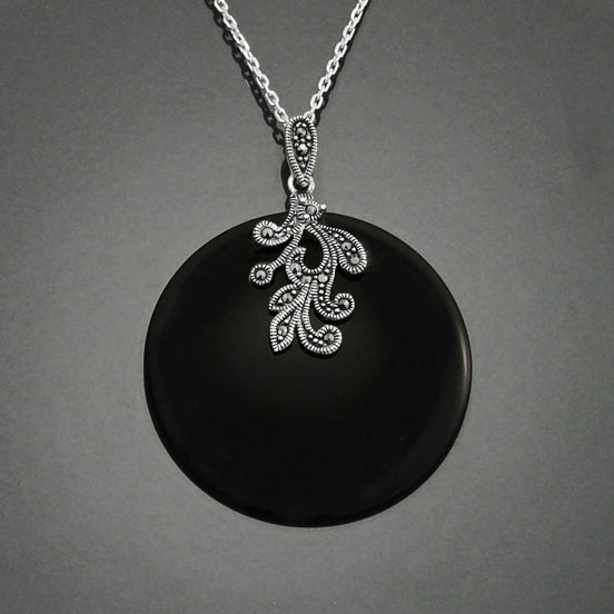 Un collier en argent avec un pendentif en onyx noir orné d'un motif vintage Art Deco détaillé en marcassite.