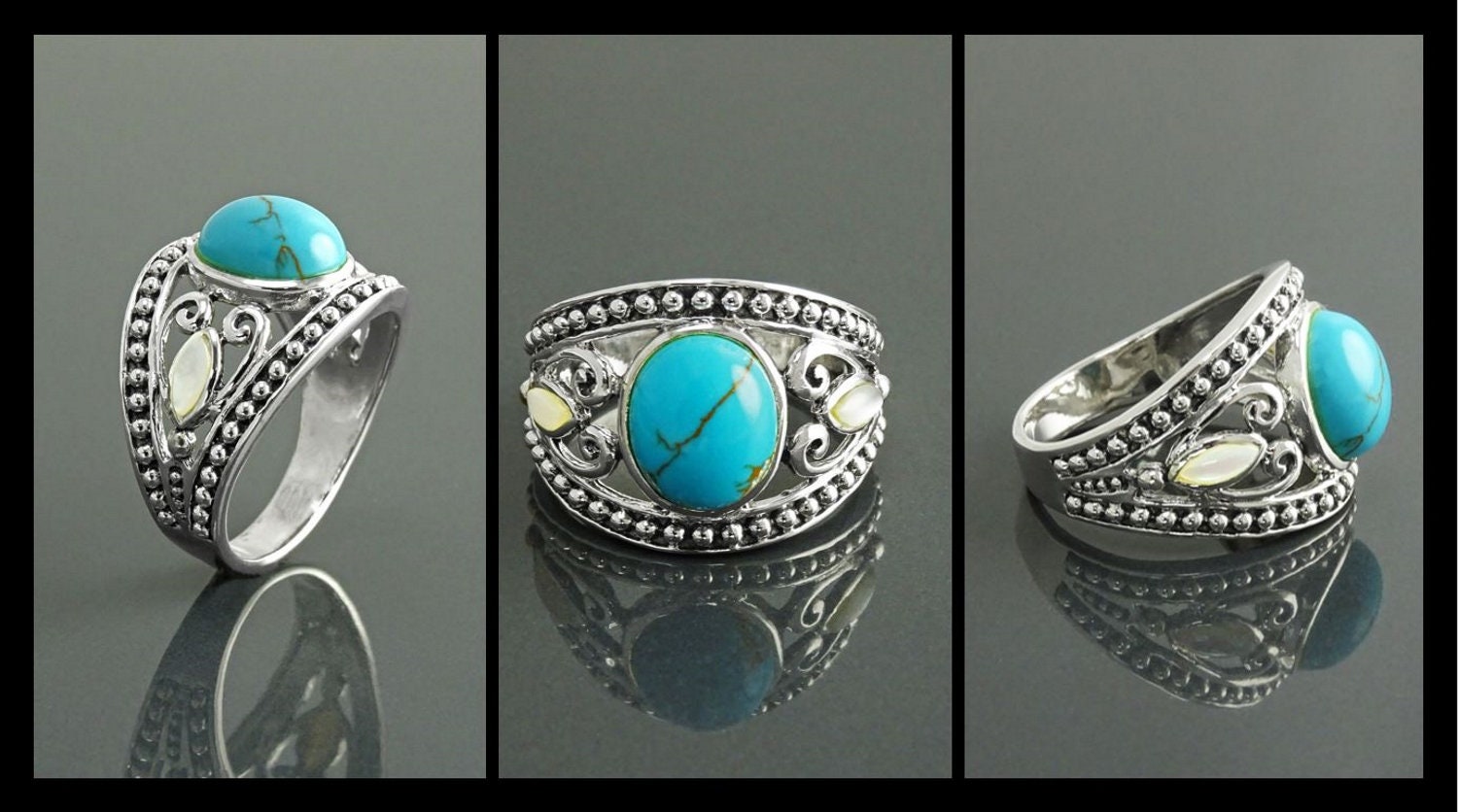 Une bague bohème en argent massif 925 avec une pierre turquoise sertie dans un motif de filigrane décoratif. La bague est ornée de deux petites nacres blanches de chaque côté de la pierre turquoise.
