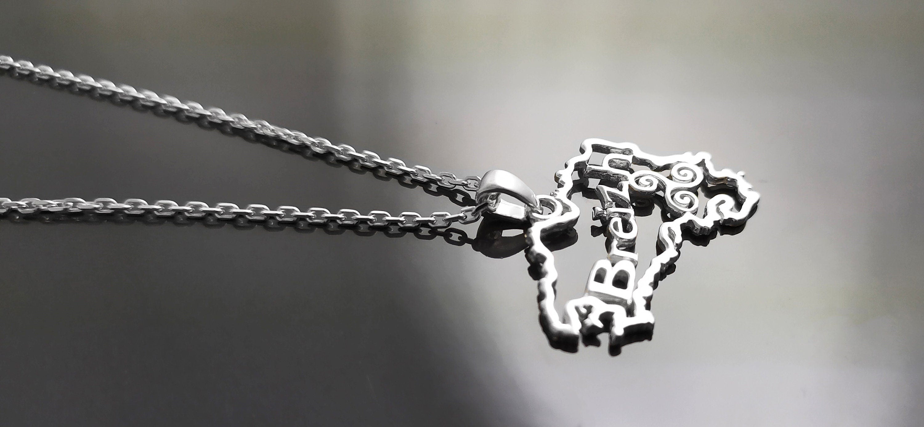 Side view of a necklace with a pendant shaped like the outline of the state of  'Breizh' (Brittany) in France. The pendant has the word 'Breizh' written inside the outline.
Brand: KRAMIKE
Product: Brittany map necklace / Breizh pendant
Metal: 925 sterling silver
Pendant size: 3.0 × 2.0 cm
Weight: 3.6 g
Symbol: Triskel (center detail)
Chain options: 45 cm / 50 cm / 55 cm
Ships from: France
Tracking: included