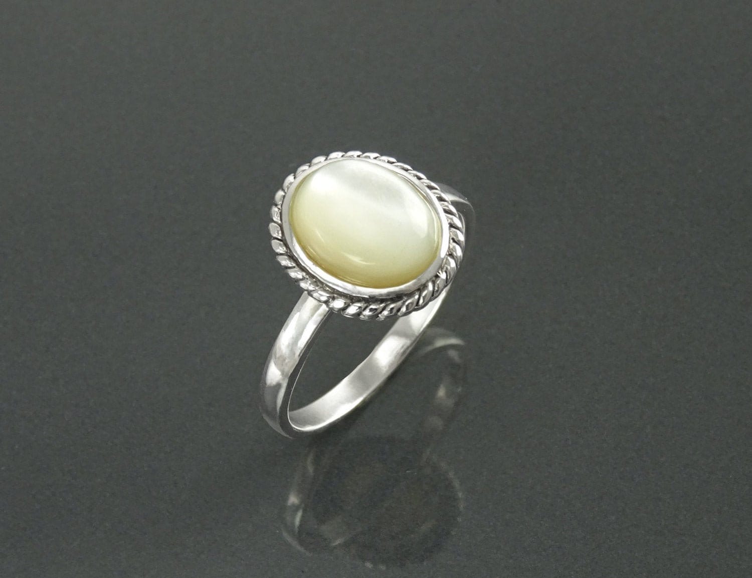 Une bague en argent 925 avec une pierre ovale blanche sertie dans une bordure en forme de corde. Un bijou artisanal durable. Fait à la main localement. Boutique de confiance recommandée par ses clients.