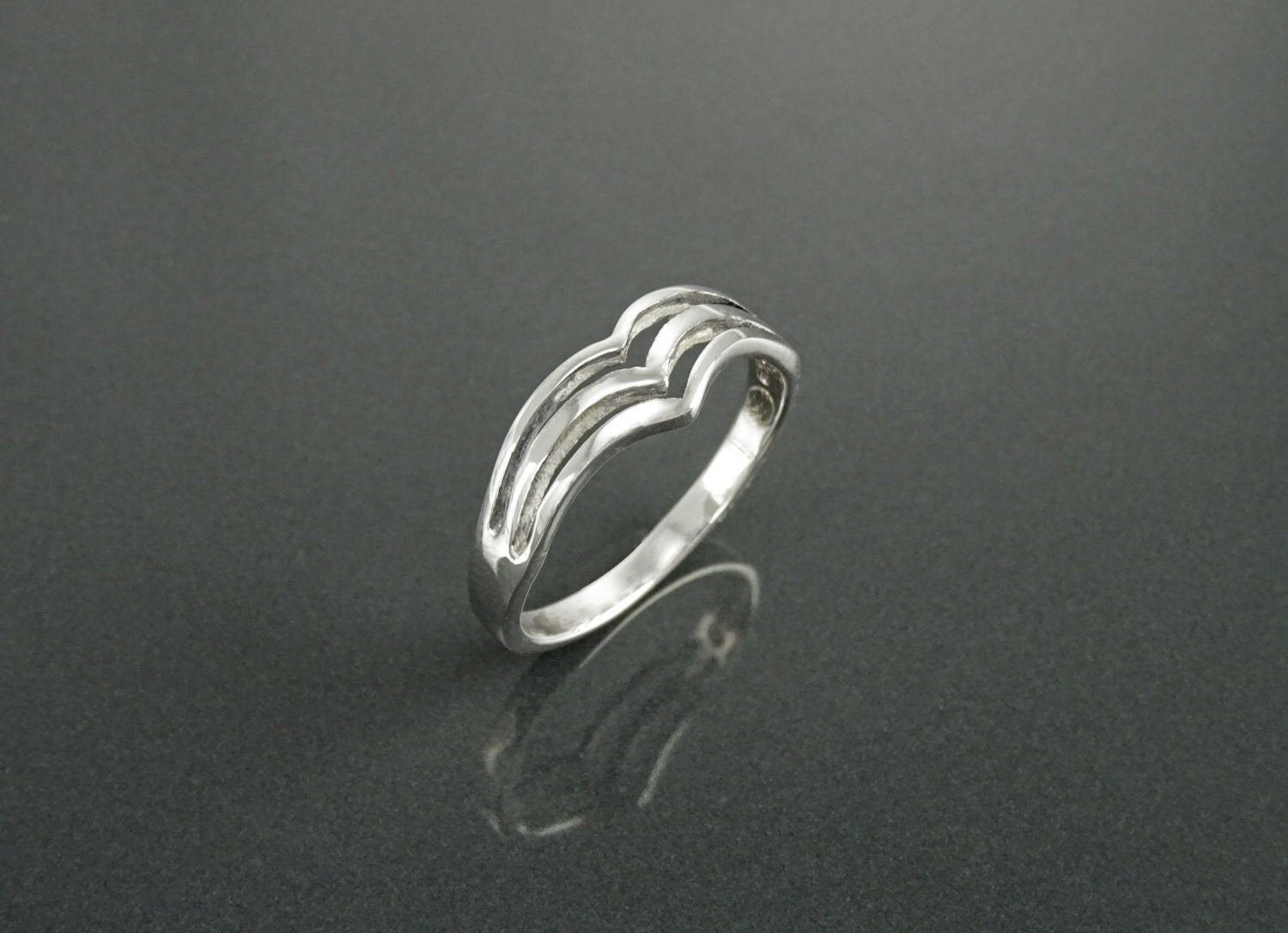 Une bague en argent massif avec un design unique composé de trois bandes superposées qui forment un cœur.