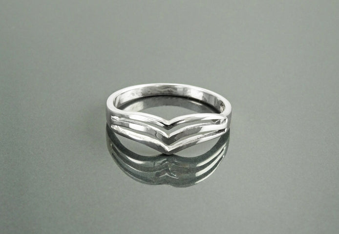 Une bague en argent 925 avec un motif triple chevron. La bague est en métal lisse et poli et a un style simple et moderne.