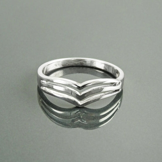 Une bague en argent 925 avec un motif triple chevron. La bague est en métal lisse et poli et a un style simple et moderne.