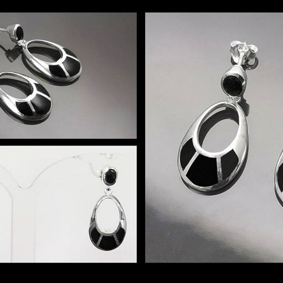 Une paire de boucles d'oreilles pendantes ovales en argent 925 avec des pierres noires en onyx. Les pierres sont serties dans un cadre en argent avec un motif géométrique.