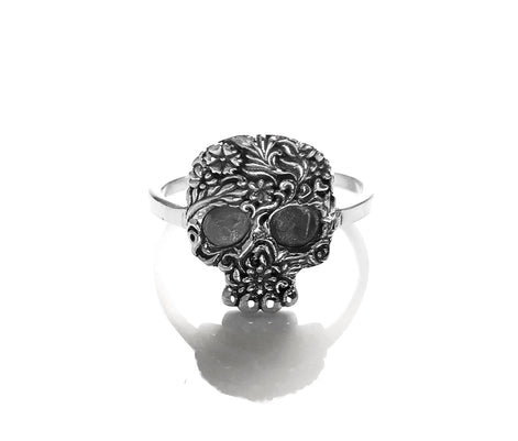 Bague en argent avec un motif de crâne détaillé. Le crâne est orné de motifs floraux complexes.
