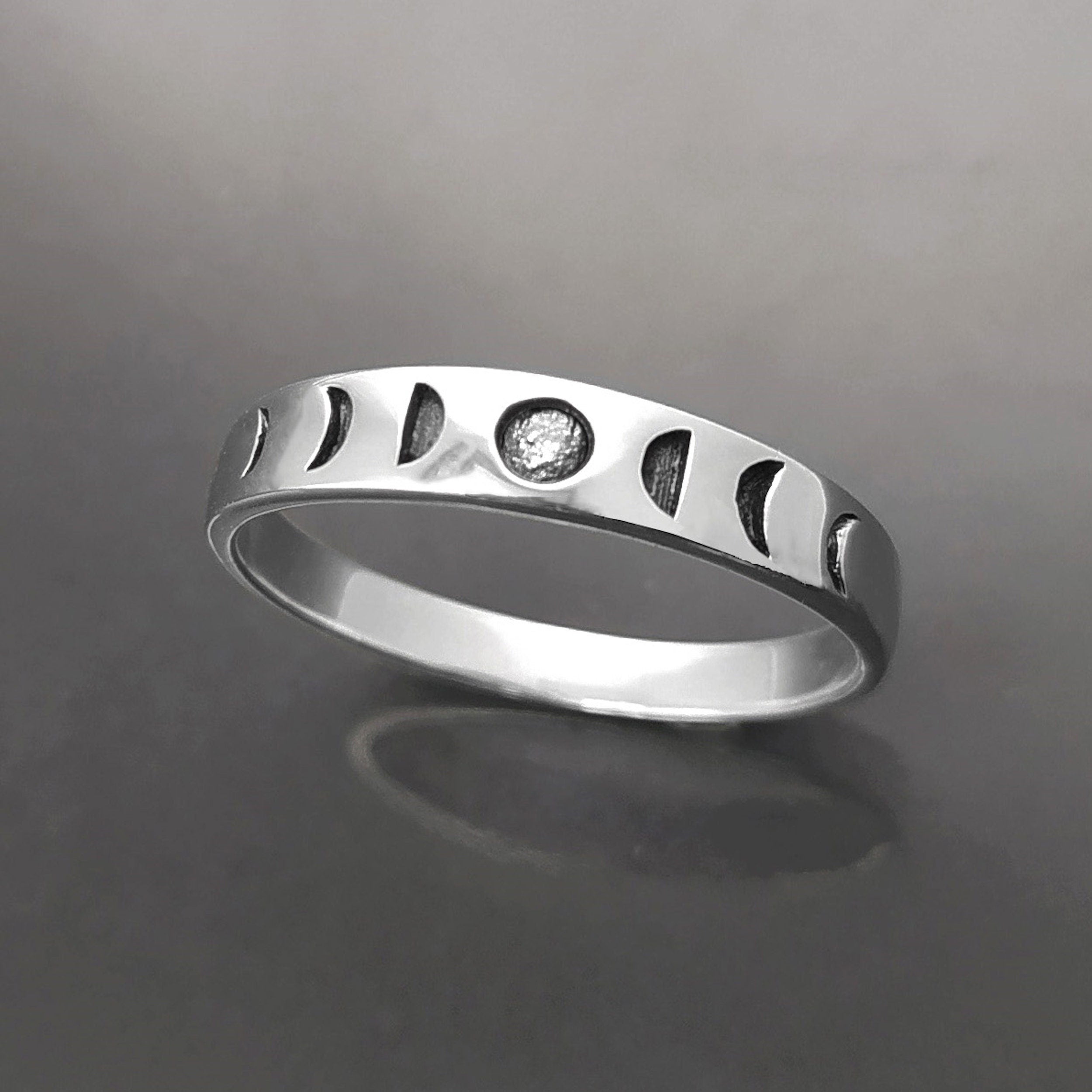 Une bague en argent avec un motif de phases lunaires. La bague présente une série de croissants de lune, chacun représentant une phase différente du cycle lunaire.
Un anneau fin et facile à porter, avec un design moderne.
Bague de haut.
Durable, fait main, local. Créateurs sûrs. Boutique aux milliers d'avis.