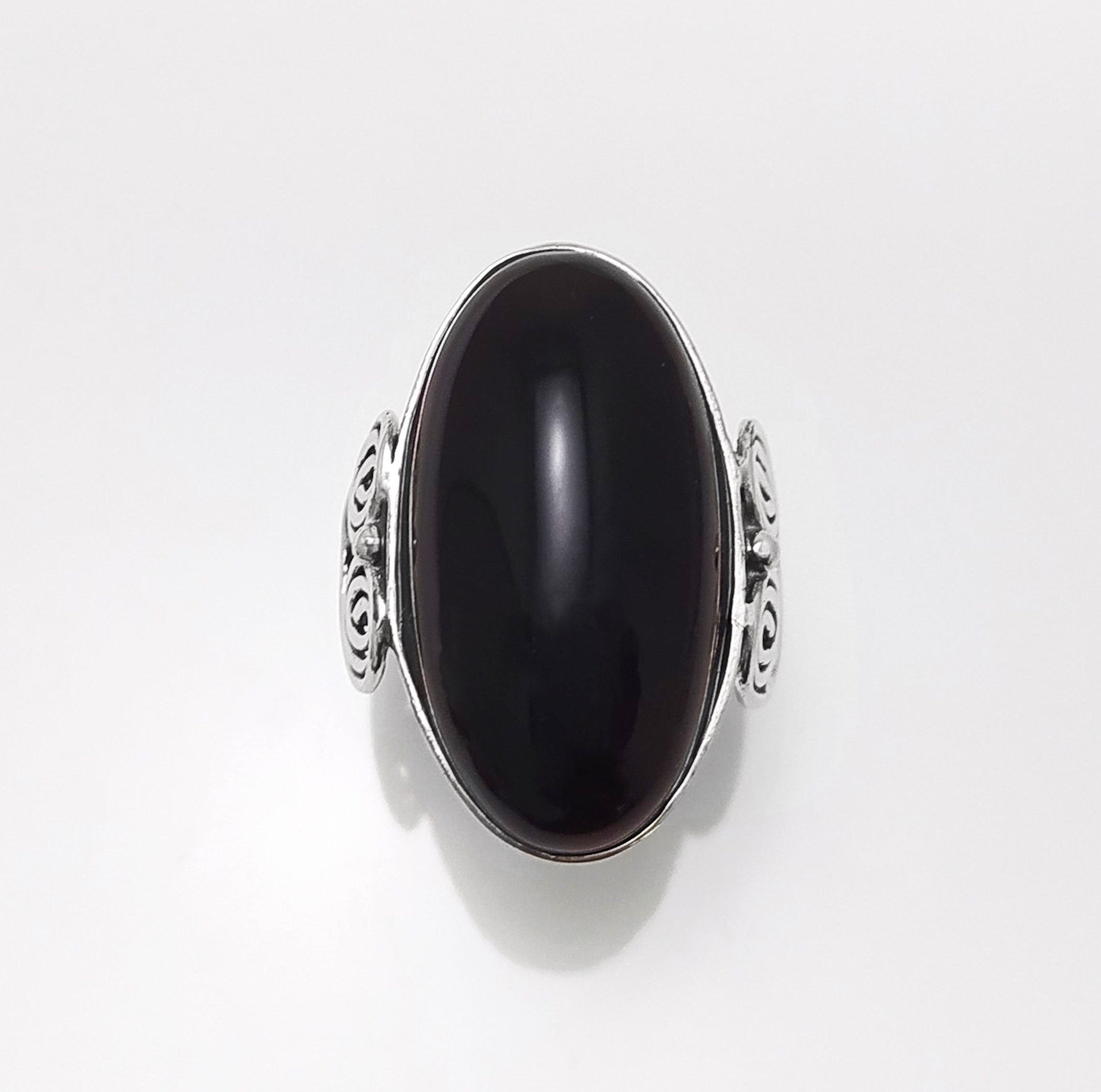Top view — Sterling Silver ring with a large oval black onyx stone. The ring has a decorative spiral pattern on the side of the band. 
• Metal: 925 sterling silver
• Stone: black onyx (cabochon)
• Stone size: 15×30 mm (approx.)
• Ring face: 15×30 mm | Band width: 3 mm
• Finish: high polish
• Handmade: yes | Country: FR
• Packaging: gift box | Resizing: on request