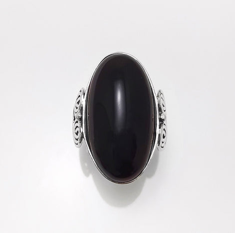 Top view — Sterling Silver ring with a large oval black onyx stone. The ring has a decorative spiral pattern on the side of the band. 
• Metal: 925 sterling silver
• Stone: black onyx (cabochon)
• Stone size: 15×30 mm (approx.)
• Ring face: 15×30 mm | Band width: 3 mm
• Finish: high polish
• Handmade: yes | Country: FR
• Packaging: gift box | Resizing: on request