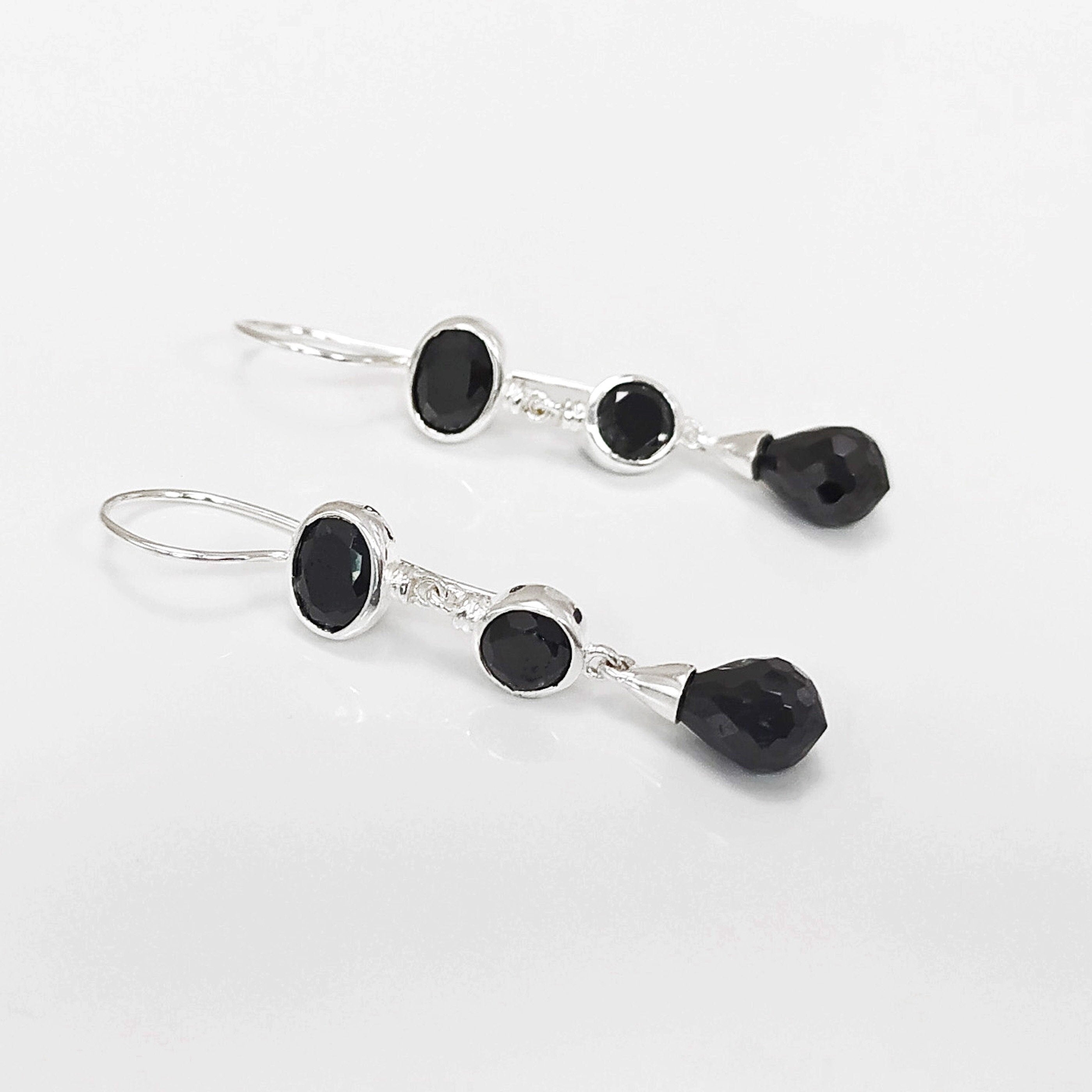 Boucles d'oreilles pendantes en argent 925 massif avec trois pierres Cz zirconium noires. La pierre du haut est ronde, la pierre du milieu est ovale et la pierre du bas a la forme d'une goutte. Longues boucles d'oreilles modernes à crochets vendues par KRAMIKE Paris