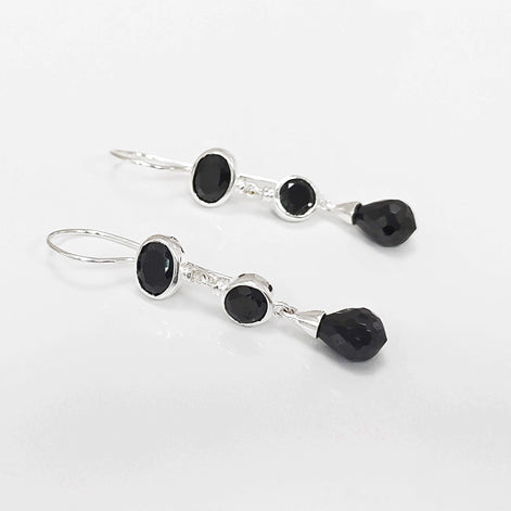 Boucles d'oreilles pendantes en argent 925 massif avec trois pierres Cz zirconium noires. La pierre du haut est ronde, la pierre du milieu est ovale et la pierre du bas a la forme d'une goutte. Longues boucles d'oreilles modernes à crochets vendues par KRAMIKE Paris