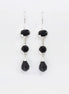 Une paire de boucles d'oreilles pendantes en argent 925 avec trois pierres Cz zirconium noires. La pierre du haut est ronde, la pierre du milieu est ovale et la pierre du bas a la forme d'une larme. Longues boucles d'oreilles à crochets en  modernes vendues par KRAMIKE Paris