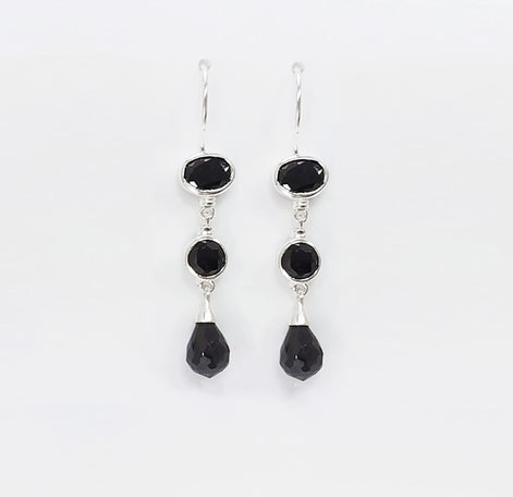 Une paire de boucles d'oreilles pendantes en argent 925 avec trois pierres Cz zirconium noires. La pierre du haut est ronde, la pierre du milieu est ovale et la pierre du bas a la forme d'une larme. Longues boucles d'oreilles à crochets en  modernes vendues par KRAMIKE Paris