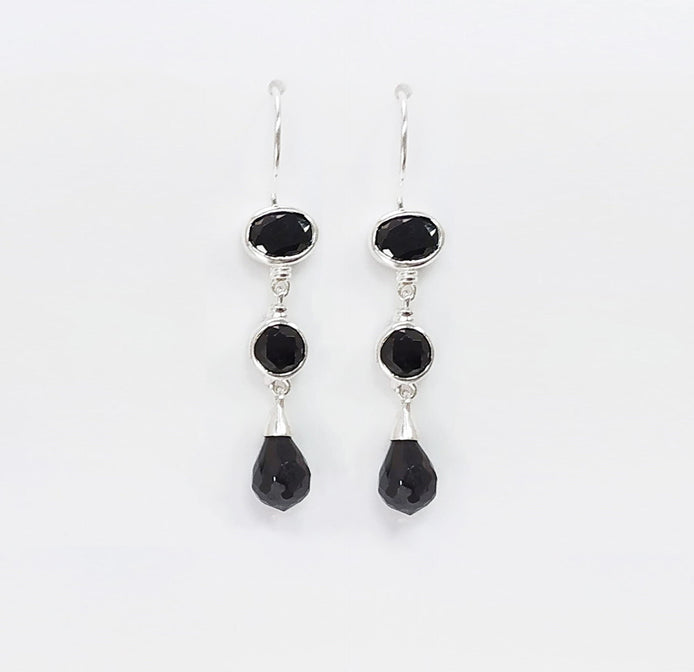 Une paire de boucles d'oreilles pendantes en argent 925 avec trois pierres Cz zirconium noires. La pierre du haut est ronde, la pierre du milieu est ovale et la pierre du bas a la forme d'une larme. Longues boucles d'oreilles à crochets en  modernes vendues par KRAMIKE Paris