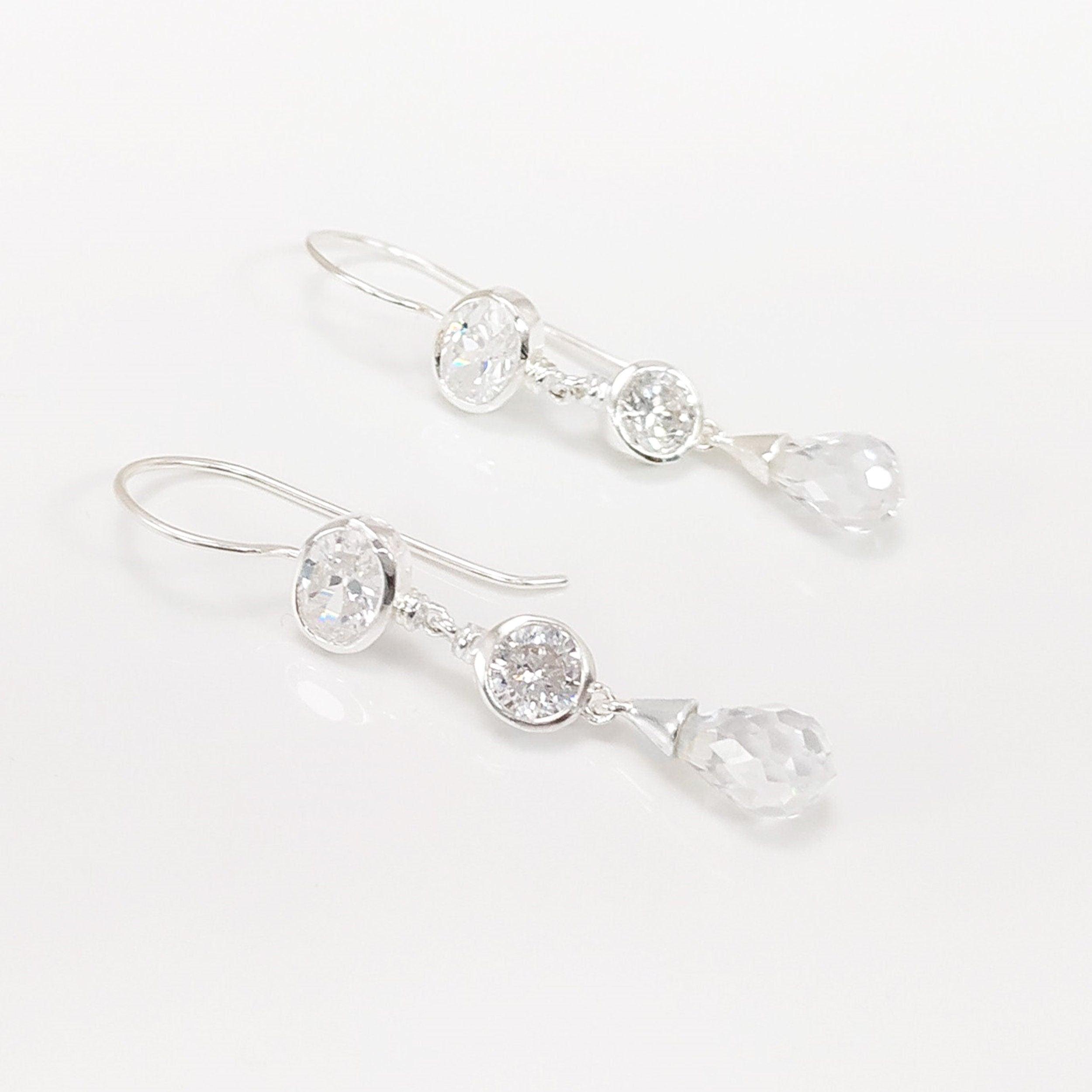 Boucles d'oreilles pendantes en argent avec des pierres de cristal claires et des breloques en forme de goutte.