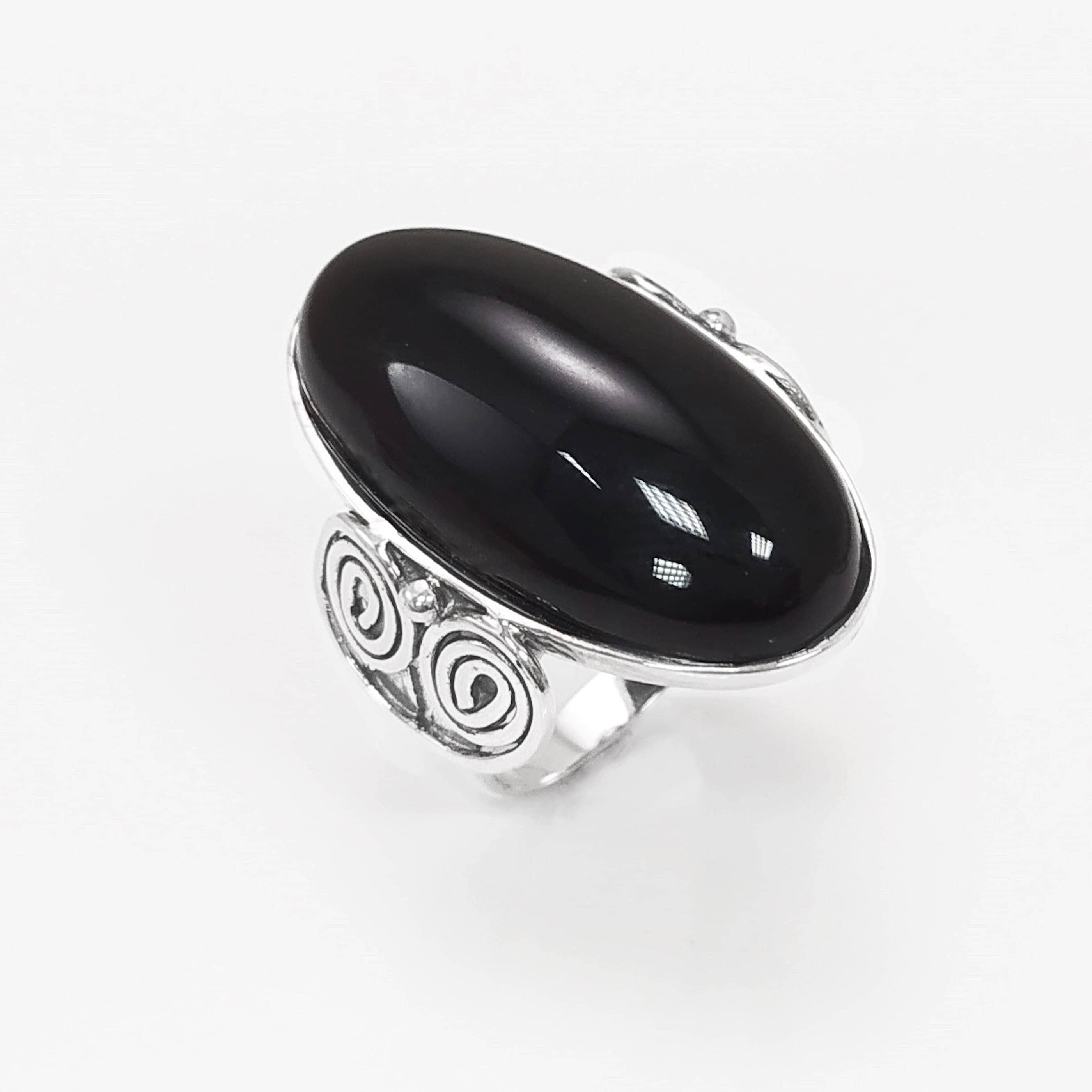 Top side view — Sterling Silver ring with a large oval black onyx stone. The ring has a decorative spiral pattern on the side of the band.
• Metal: 925 sterling silver
• Stone: black onyx (cabochon)
• Stone size: 15×30 mm (approx.)
• Ring face: 15×30 mm | Band width: 3 mm
• Finish: high polish
• Handmade: yes | Country: FR
• Packaging: gift box | Resizing: on request