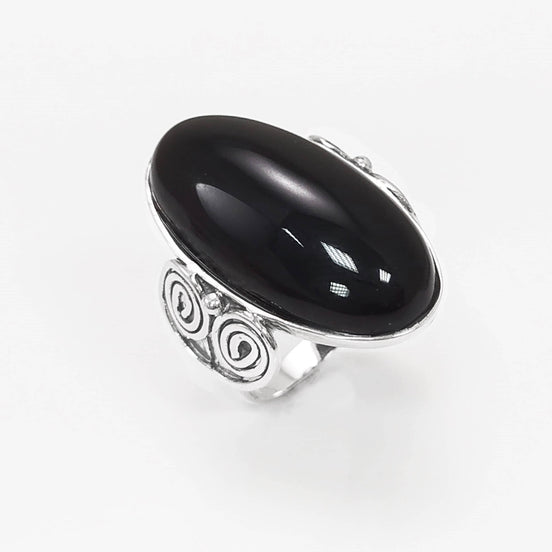 Top side view — Sterling Silver ring with a large oval black onyx stone. The ring has a decorative spiral pattern on the side of the band.
• Metal: 925 sterling silver
• Stone: black onyx (cabochon)
• Stone size: 15×30 mm (approx.)
• Ring face: 15×30 mm | Band width: 3 mm
• Finish: high polish
• Handmade: yes | Country: FR
• Packaging: gift box | Resizing: on request