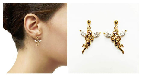 Boucles d'oreilles ange dorées avec des ailes et des accents en cristal transparent. Les boucles d'oreilles présentent une figurine de fée détaillée dans un design pendant. Les boucles d'oreilles sont présentées sur fond blanc et portées.