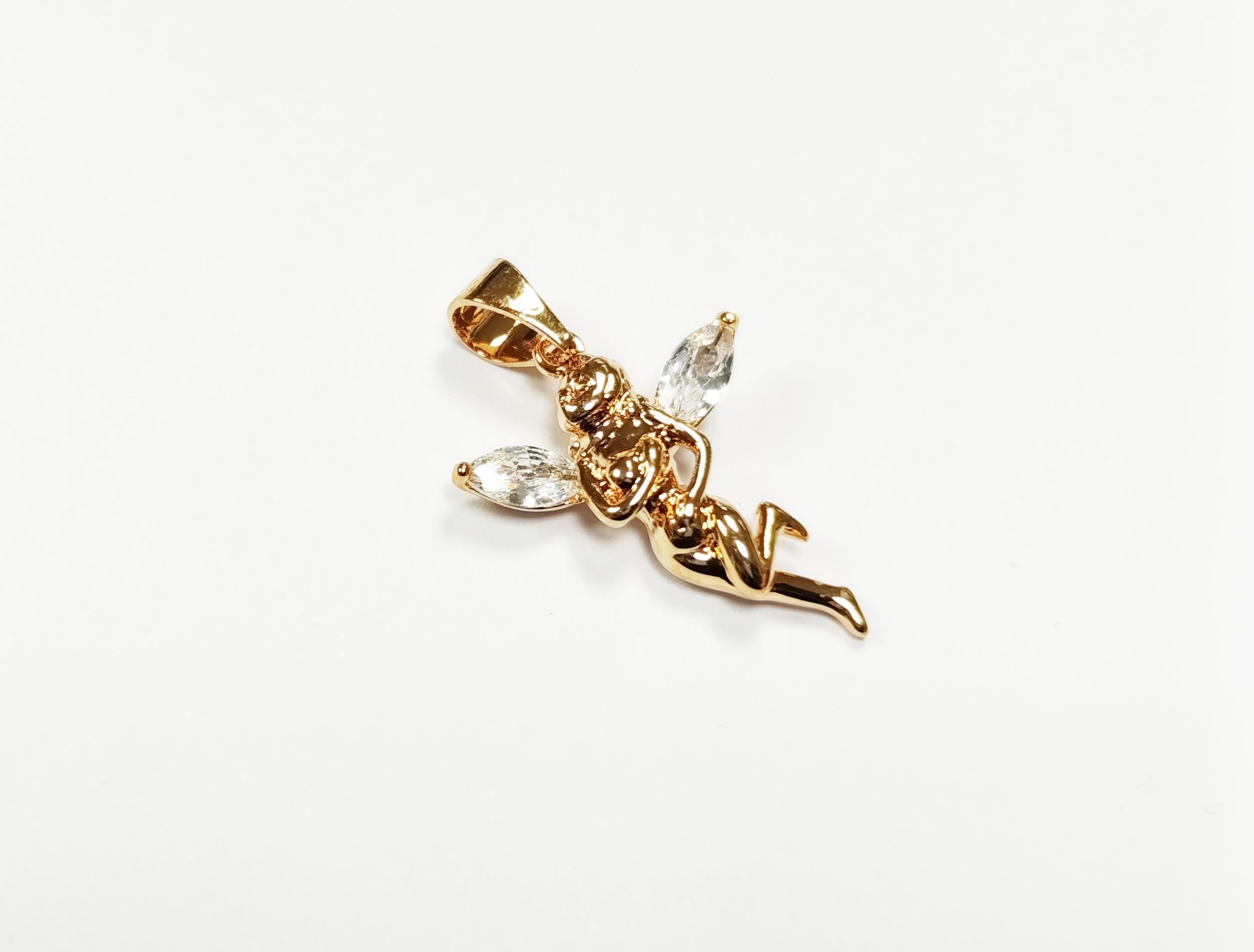 Un pendentif doré en forme de fée, orné de cristaux transparents en forme de goutte pour les ailes. La fée est en position de vol, avec des détails complexes. Le pendentif est sur fond blanc.