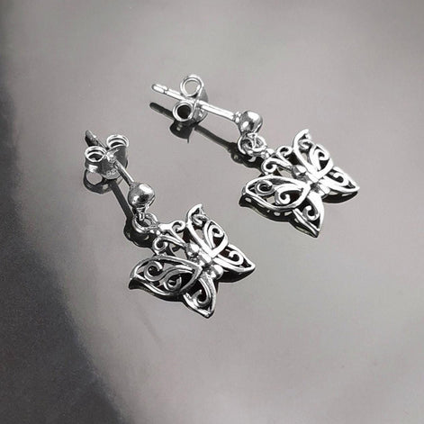 Une paire de boucles d'oreilles pendantes en argent en forme de papillon. Les boucles d'oreilles présentent un design délicat et complexe avec un motif de filigrane. 
Boucles d'oreilles papillon en Argent 925, Symbole de la Métamorphose, du renouvellement et du commencement d'un nouveau chapitre de vie.
Boucles vu de face. Des Papillons en filigrane sur tige.
Durable, fait main, local. Créateurs sûrs. Boutique aux milliers d'avis.