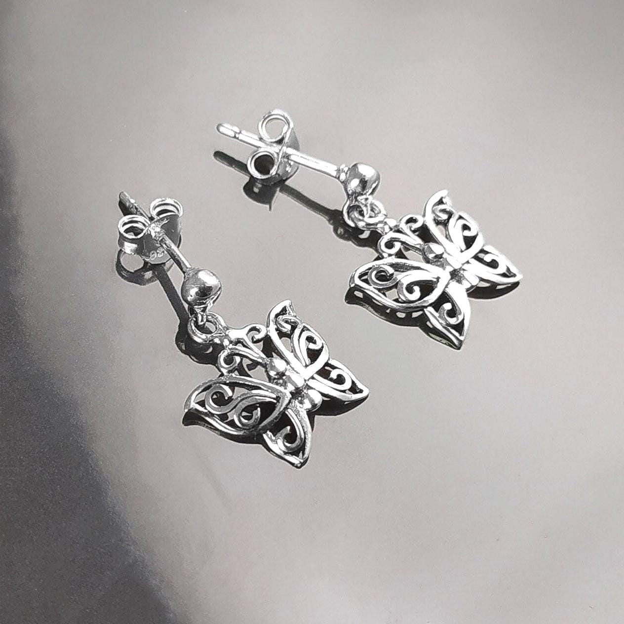 Une paire de boucles d'oreilles pendantes en argent en forme de papillon. Les boucles d'oreilles présentent un design délicat et complexe avec un motif de filigrane. 
Boucles d'oreilles papillon en Argent 925, Symbole de la Métamorphose, du renouvellement et du commencement d'un nouveau chapitre de vie.
Boucles vu de face. Des Papillons en filigrane sur tige.
Durable, fait main, local. Créateurs sûrs. Boutique aux milliers d'avis.