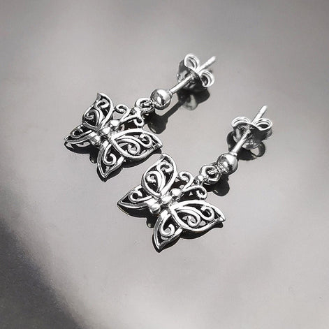 Une paire de boucles d'oreilles pendantes en argent en forme de papillon. Les boucles d'oreilles présentent un design délicat et complexe avec un motif de filigrane. 
Boucles d'oreilles papillon en Argent 925, Symbole de la Métamorphose, du renouvellement et du commencement d'un nouveau chapitre de vie.
Boucles vu de face. Des Papillons en filigrane sur tige.
Durable, fait main, local. Créateurs sûrs. Boutique aux milliers d'avis.