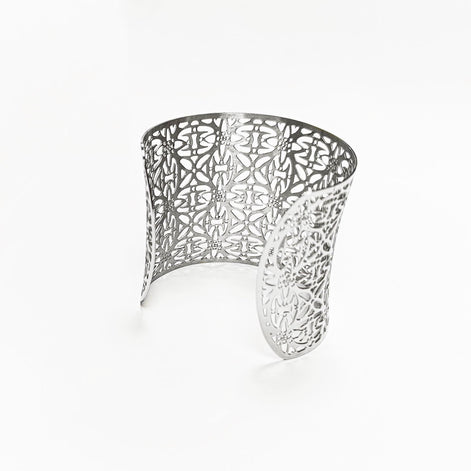 Back view — Silver-colored open cuff bracelet with an openwork floral design. The bracelet has a wide band that tapers slightly towards the opening, easy to slip on. The intricate pattern is visible throughout the entire piece, creating a delicate and elegant look.

Brand: KRAMIKE
Type of jewelry: cuff / statement armor cuff
Metal: stainless steel
Color: silver-tone
Style: Filigree floral lace / modern boho 
Diameter: 66 mm
Width: 60 mm
Ships from: France