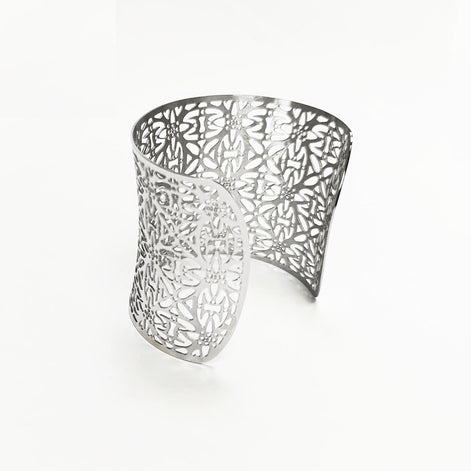 A silver-colored open cuff bracelet with a floral cutout design. The wide bracelet curves around, showcasing intricate patterns. The openwork design allows light to pass through, creating a delicate and airy aesthetic. This piece is a statement accessory.

Brand: KRAMIKE
Type of jewelry: cuff / statement armor cuff
Metal: stainless steel
Color: silver-tone
Style: Filigree floral lace / modern boho
Diameter: 66 mm
Width: 60 mm
Ships from: France