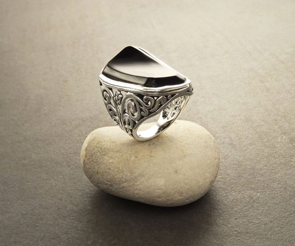 Black Filigree Ring, Sterling Silver, Curved Black Onyx Stone, Vintage Lace Design, Victorian Jewelry, Long Rectangle gemstone. La bague est posée sur une pierre blanche.