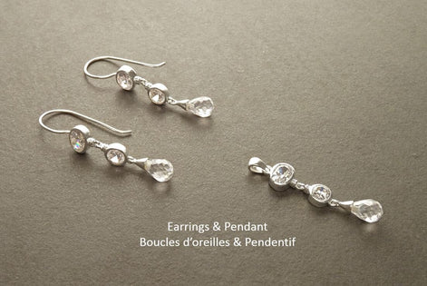 Une paire de boucles d'oreilles et un pendentif en argent avec des gouttes de cristal clair. Les boucles d'oreilles et le pendentif comportent chacun trois pierres de cristal.