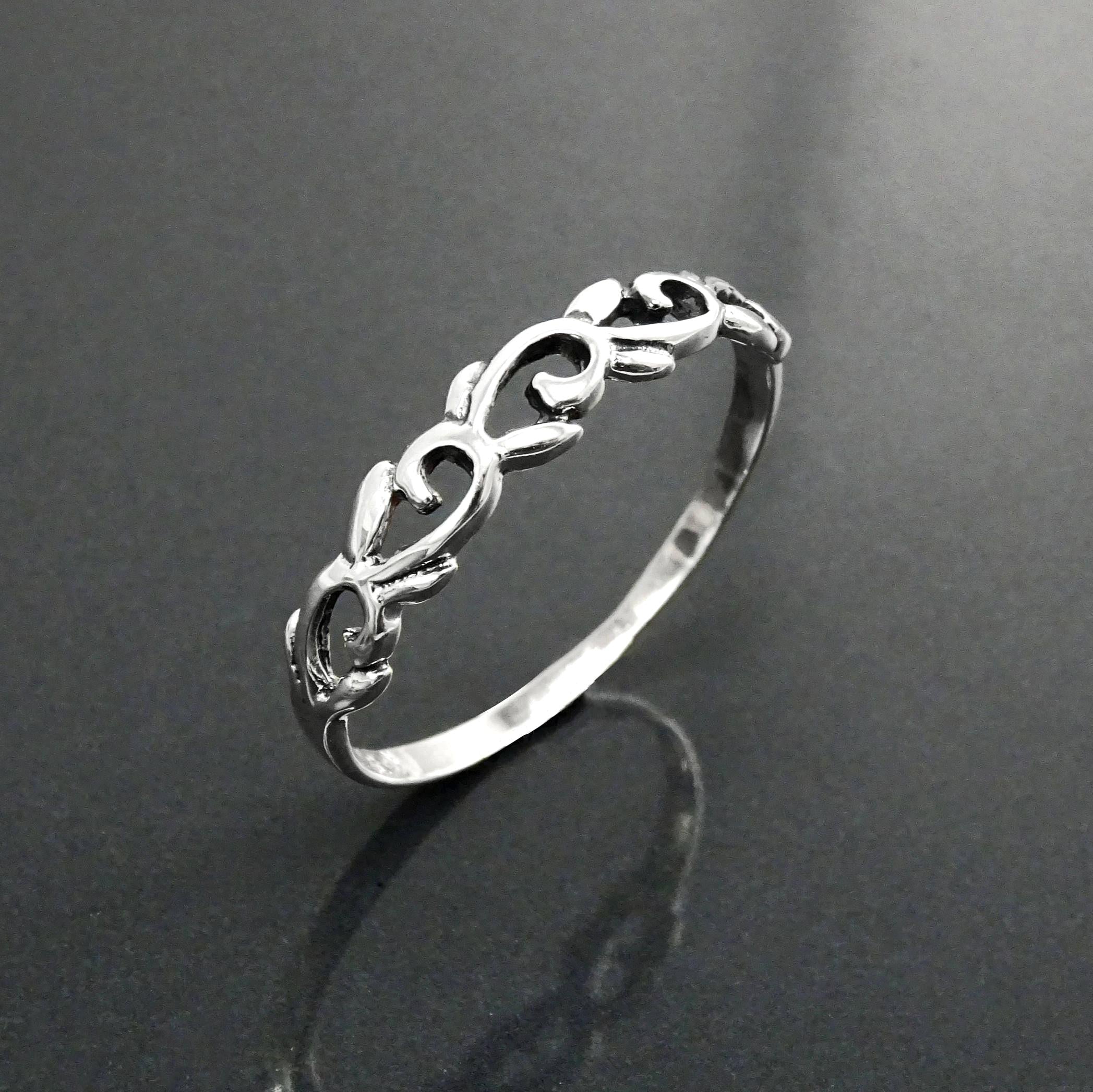 Une bague en argent massif 925 avec un anneau fin et arrondi avec un motif incurvé en relief sur la face. La bague a une finition polie, reflétant la lumière. La bague est un anneau à motif filigrané. Vu sur le côté, bague posée à la verticale.
Qualité artisanale sûre. Local. Durable. Boutique de confiance recommandée.