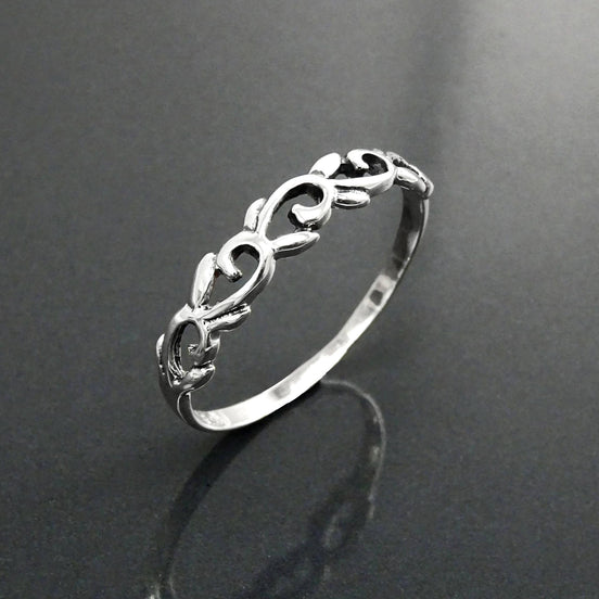 Une bague en argent massif 925 avec un anneau fin et arrondi avec un motif incurvé en relief sur la face. La bague a une finition polie, reflétant la lumière. La bague est un anneau à motif filigrané. Vu sur le côté, bague posée à la verticale.
Qualité artisanale sûre. Local. Durable. Boutique de confiance recommandée.