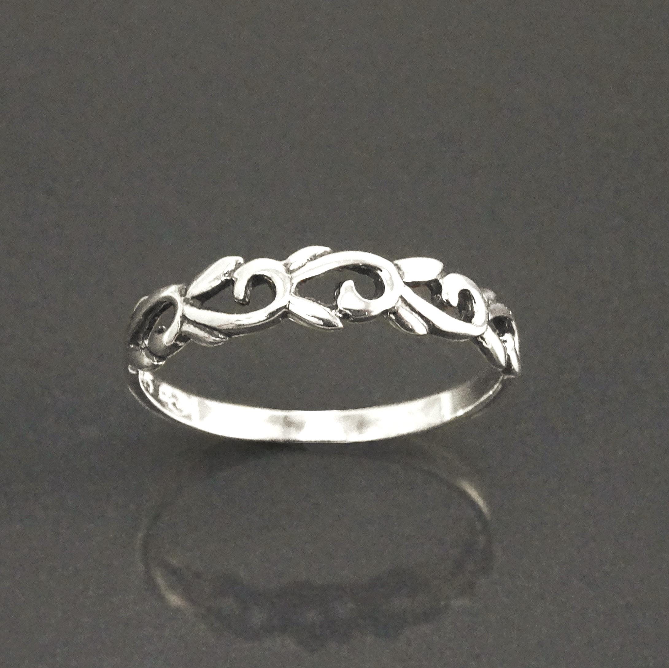 Une bague en argent massif 925 avec un anneau fin et arrondi avec un motif incurvé en relief sur la face. La bague a une finition polie, reflétant la lumière. La bague est un anneau à motif filigrané. Vu sur le côté.
Qualité artisanale sûre. Local. Durable. Boutique de confiance recommandée.