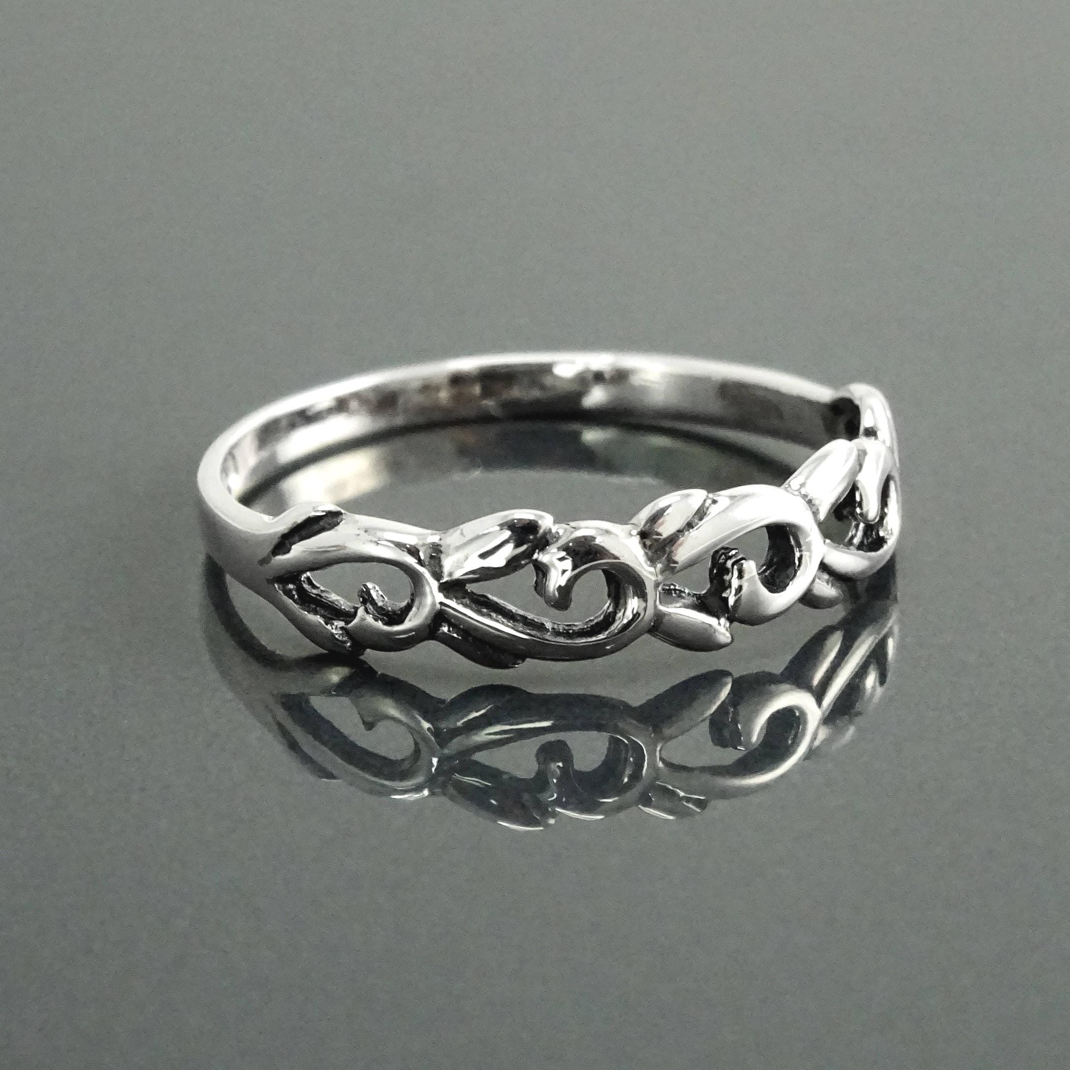Une bague en argent massif 925 avec un anneau fin et arrondi avec un motif incurvé en relief sur la face. La bague a une finition polie, reflétant la lumière. La bague est un anneau à motif filigrané. Vu sur le côté.
Qualité artisanale sûre. Local. Durable. Boutique de confiance recommandée.