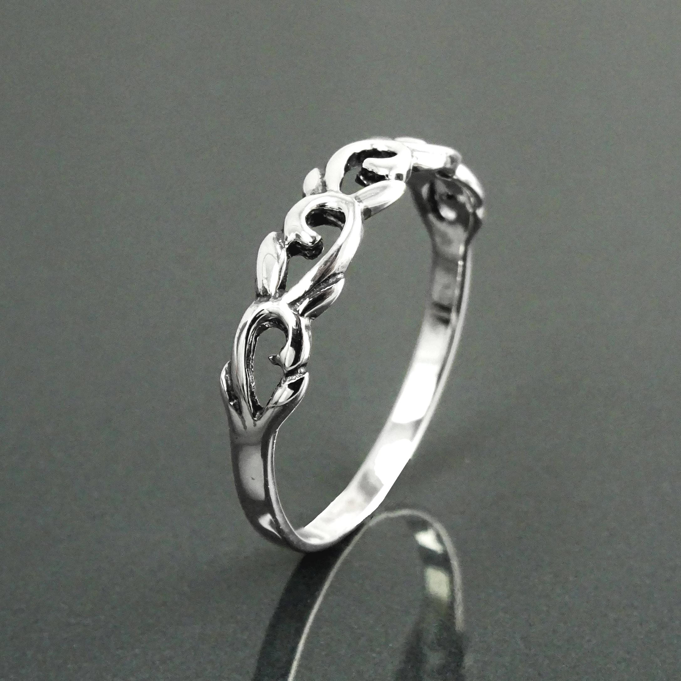 Une bague en argent massif 925 avec un anneau fin et arrondi avec un motif incurvé en relief sur la face. La bague a une finition polie, reflétant la lumière. La bague est un anneau à motif filigrané. Vu sur le côté debout.
Qualité artisanale sûre. Local. Durable. Boutique de confiance recommandée.