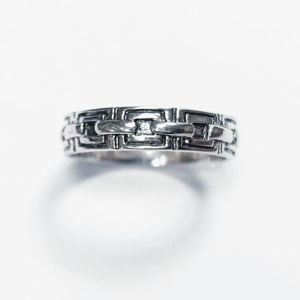 Une bague en argent massif 925 avec un motif Chaînage.
La bague présente un motif détaillé de chaînes entrelacés, créant une surface texturée. Plusieurs vues mettent en valeur le savoir-faire et le design complexe de la bague.
Vu bague de face.
Artisanat durable local. Fait main. Boutique de confiance aux milliers de ventes.