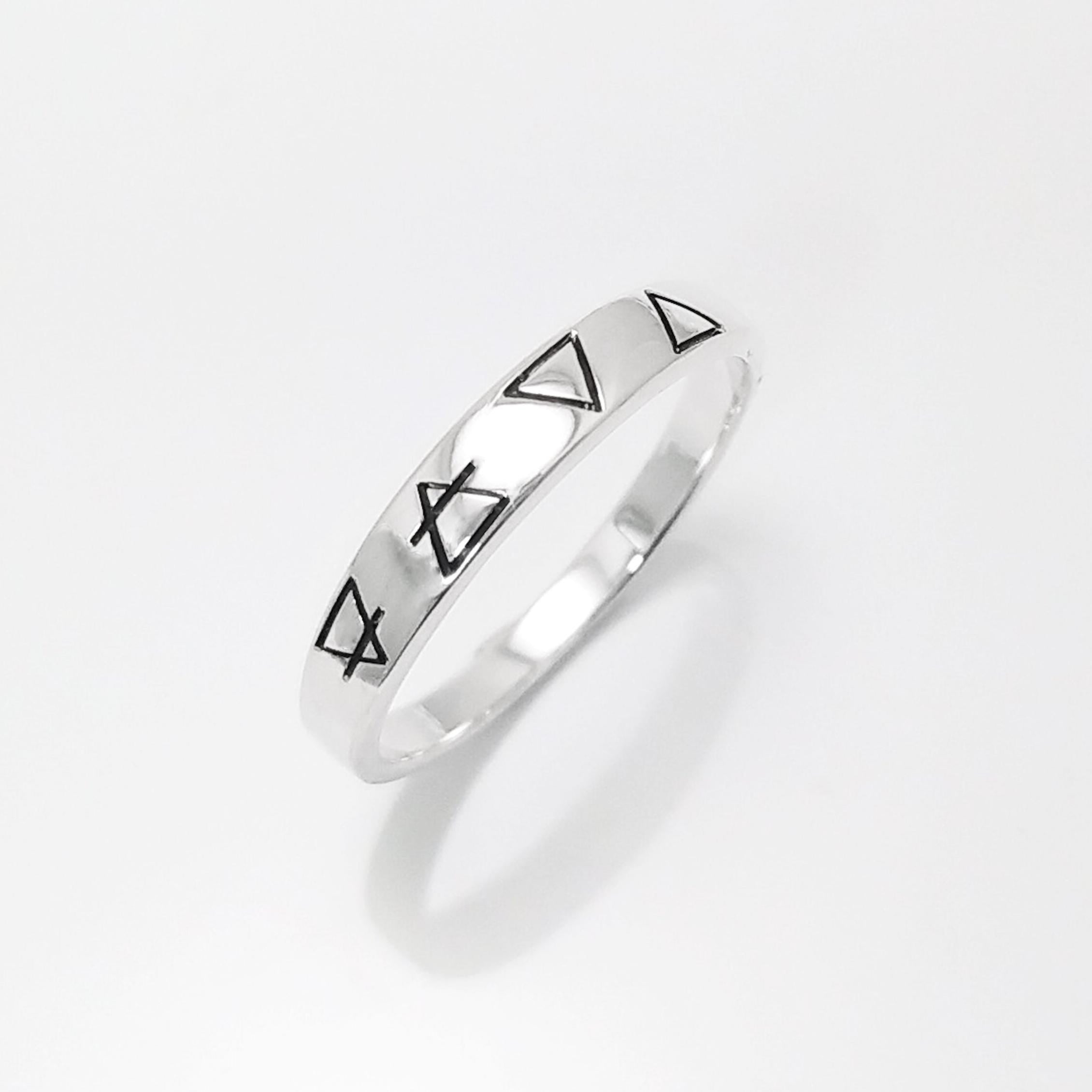 Une bague en argent avec quatre symboles gravés : un cercle avec une ligne qui le traverse, un triangle, un triangle inversé et un triangle avec une ligne qui le traverse.
Bague quatre éléments de la Planète Terre, argent 925, anneau des 4 élément symboles terrien : terre air eau feu, bijoux astrologie .
VU DE Côté.
Bijou artisanal durable. Fait main local. Boutique de confiance recommandée.
