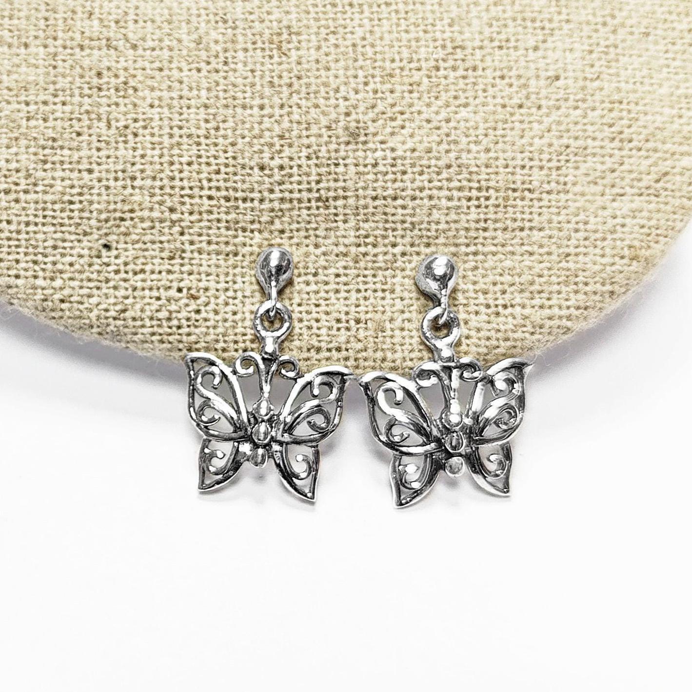 Une paire de boucles d'oreilles pendantes en argent en forme de papillon. Les boucles d'oreilles présentent un design délicat et complexe avec un motif de filigrane. 
Boucles d'oreilles papillon en Argent 925, Symbole de la Métamorphose, du renouvellement et du commencement d'un nouveau chapitre de vie.
Boucles vu de face. Des Papillons en filigrane sur tige.
Durable, fait main, local. Créateurs sûrs. Boutique aux milliers d'avis.