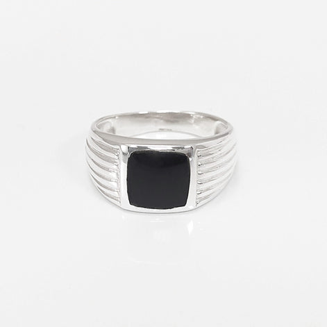 Peut inclure: Une bague en argent avec une pierre carrée noire sertie au centre. La bande de la bague a un design texturé.